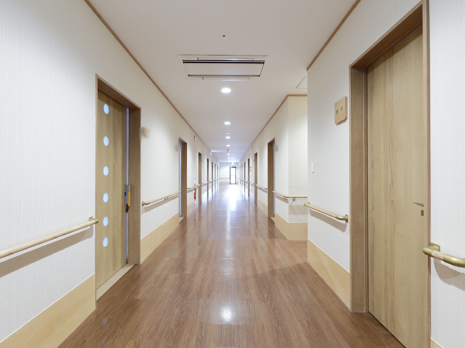 フローリングの廊下の両側には手すりが設置されている。空調完備でいつも快適。各部屋のドアの左上に表札がある。