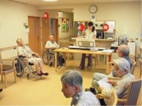 テーブルにエレクトーンを置いて演奏をするスタッフを見る入居者様