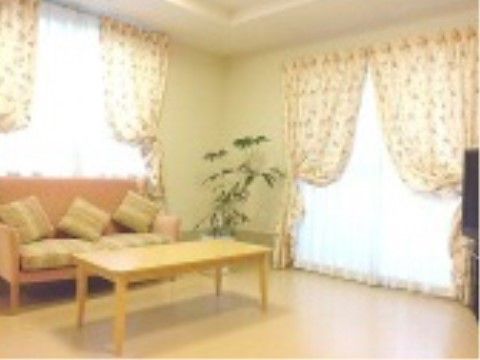 フローリングの部屋にピンク色のソファーとローテーブルが置いてある。観葉植物が飾られ、ソファーにクッションが並べられている。