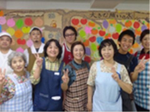 大きな木をデザインした紙の作品の前に集まったスタッフ