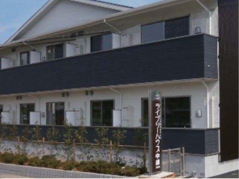 一般的なマンションのような見た目の白い建物。大きな窓はベランダにつながっている。ベランダは目隠し効果も高い柵が取り付けられている。
