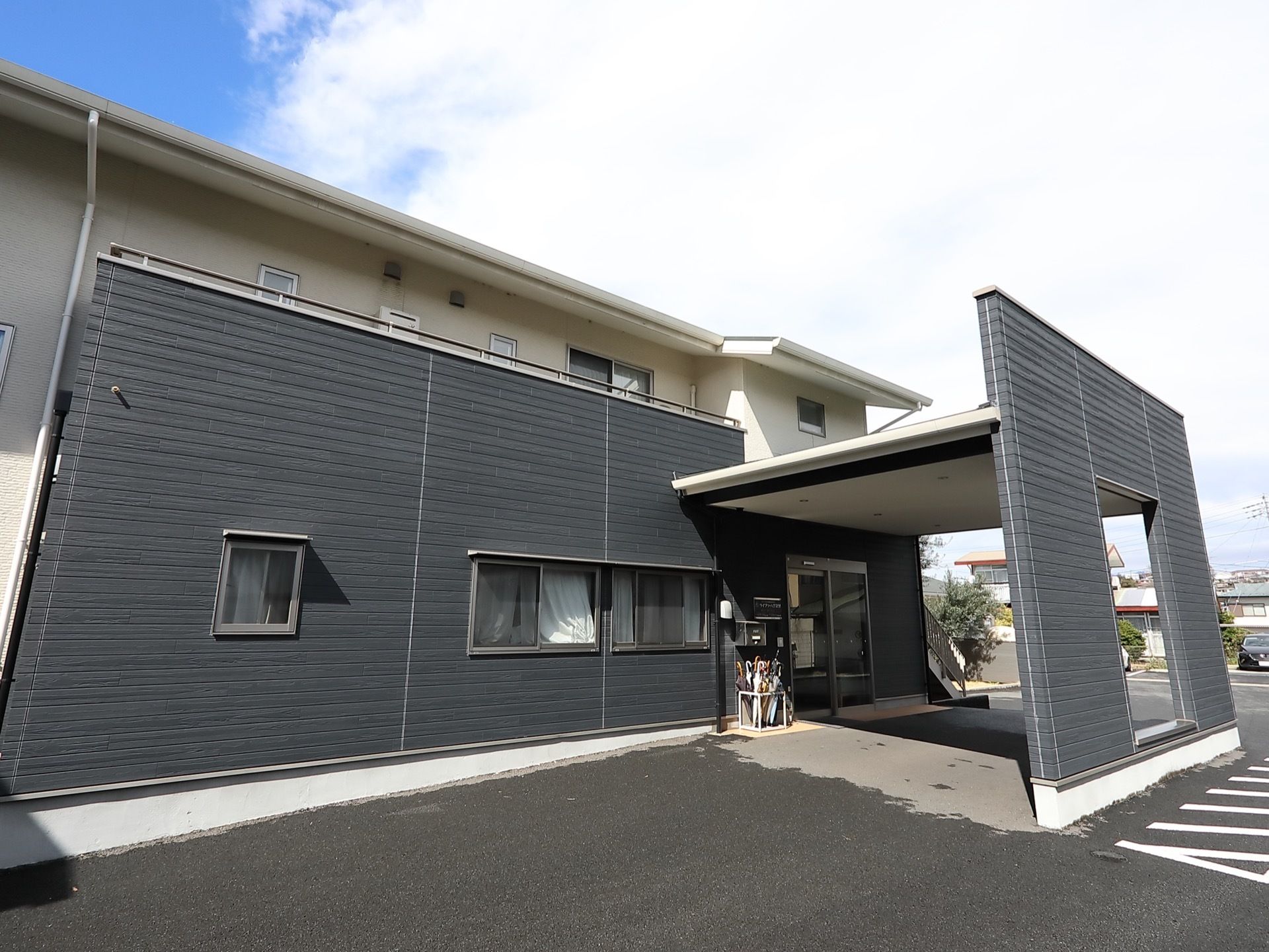 白とグレーのコントラストが印象的なデザインの外観。エントランスには屋根が設置されているので、天候の悪い日でも利用しやすくなっている。