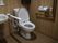 温水洗浄便座が設置されたトイレの壁に手すり、緊急呼出ボタンが設置されている。トイレの横には洗面台がある。