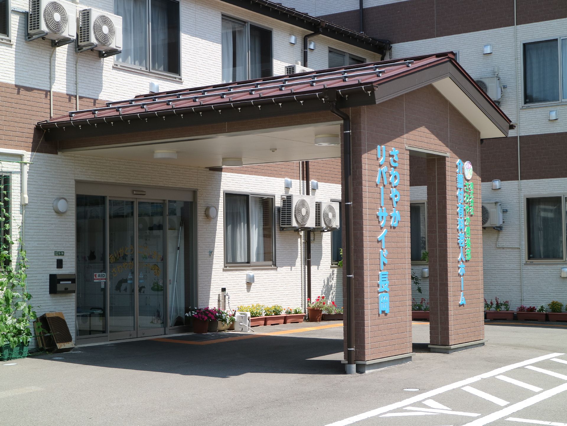 水色と緑の字で施設名が書かれた壁で支えられた屋根がある玄関