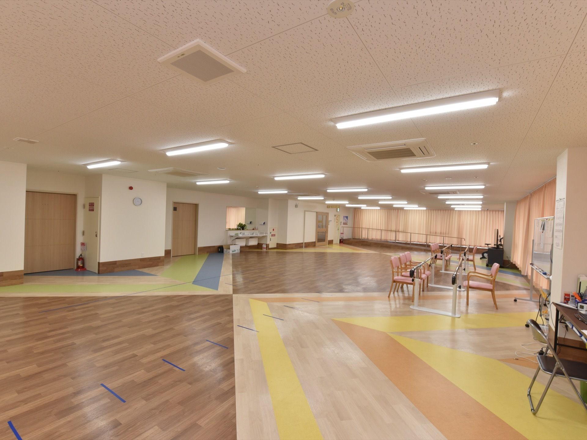 機能訓練室の壁際には各種リハビリ機器が置かれている。消火栓が備わっている。空調が完備されており、年中快適に過ごすことができる。