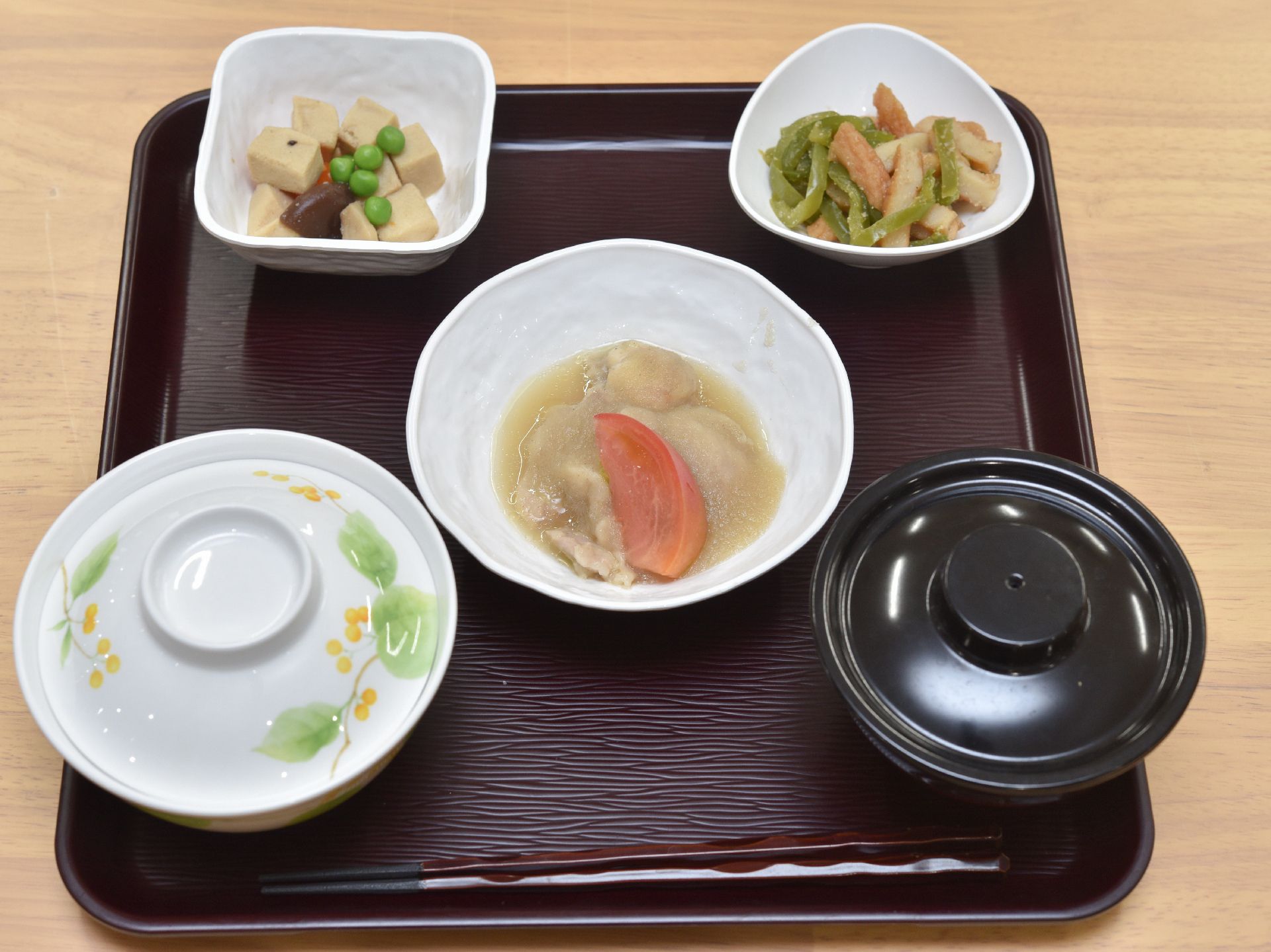 合計５品が茶色のお盆の上に上品に並べられている。ご飯とお吸い物には冷めないように蓋をしている。栄養バランスに十分配慮されている。