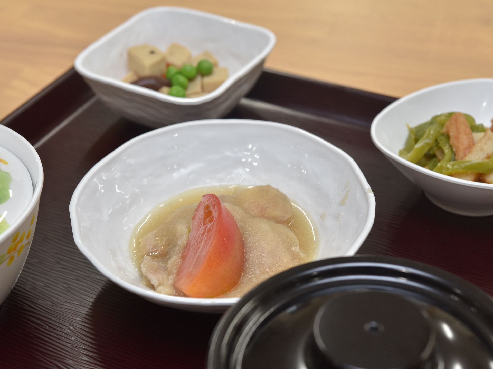 お麩とトマトの煮物や高野豆腐などが並べられた食事の例