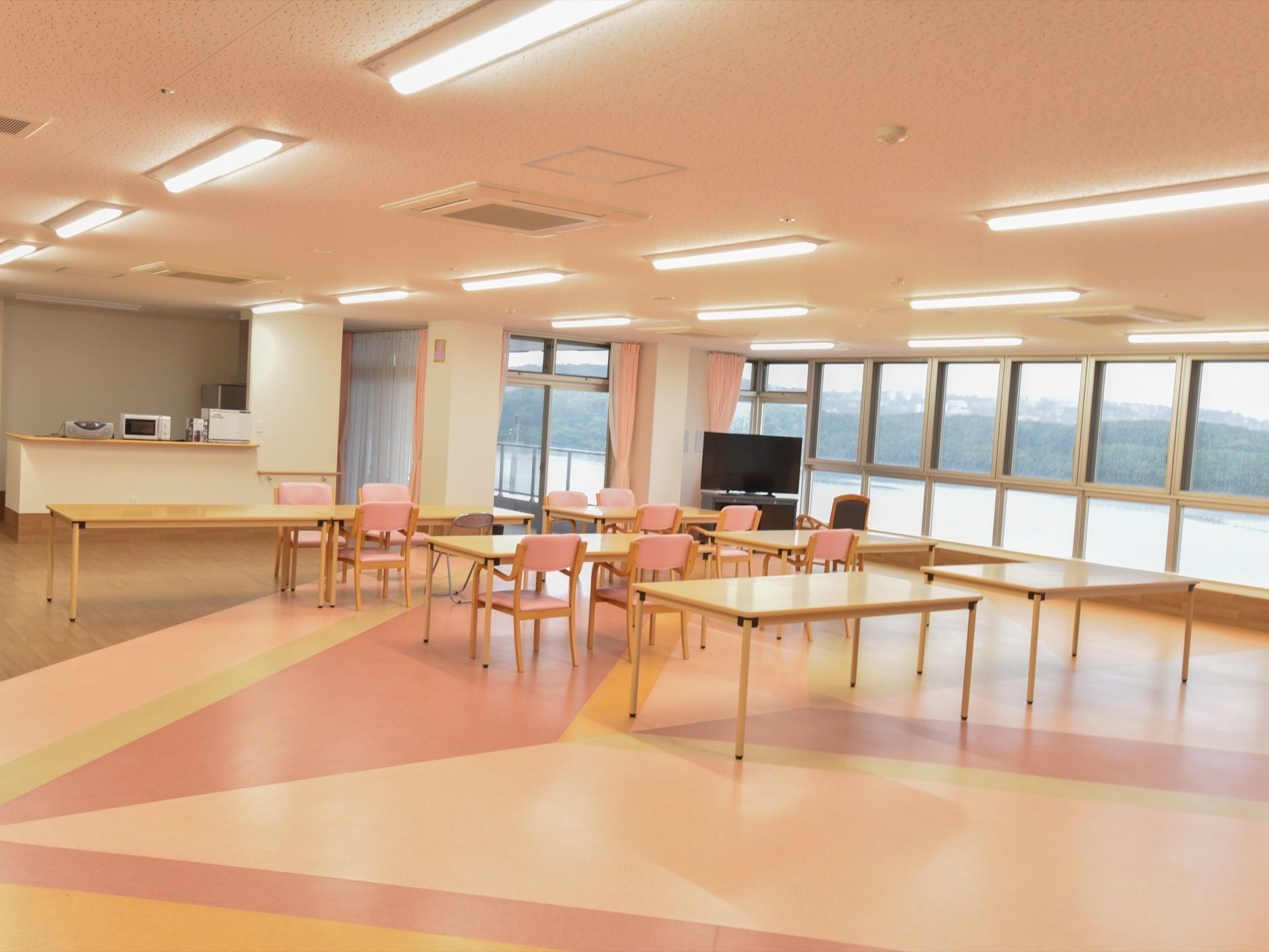 車椅子に乗った入居者様の周囲に集まって笑っている人達