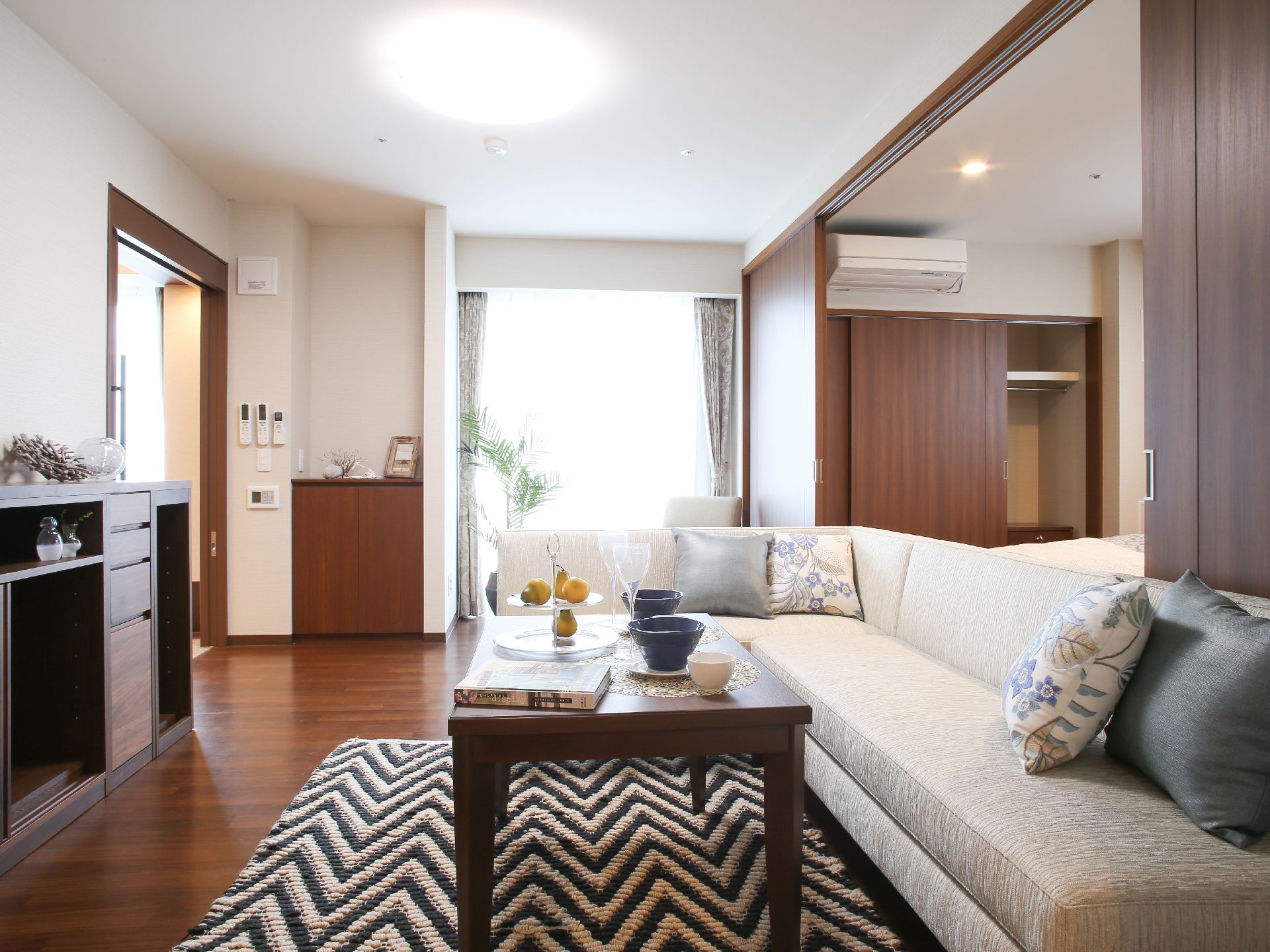 モノトーンのカーペットに、木製のテーブルが置かれている。複数の人が座ることができる、長いソファを完備。