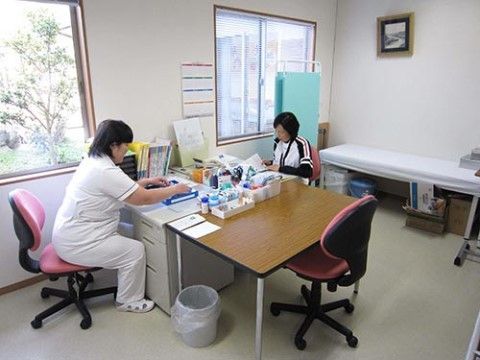 事務机に広げられた書類の処理をしている２人の女性スタッフ