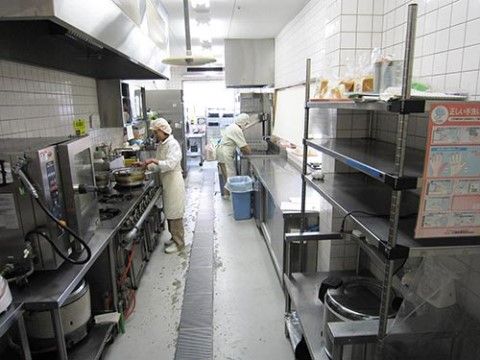ステンレス製の機材が並べられた奥行のある業務用キッチン