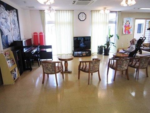 テレビ、椅子、テーブル、ピアノ、雑誌などが置かれ、入居者様が思い思いに過ごすことができるリビングである。