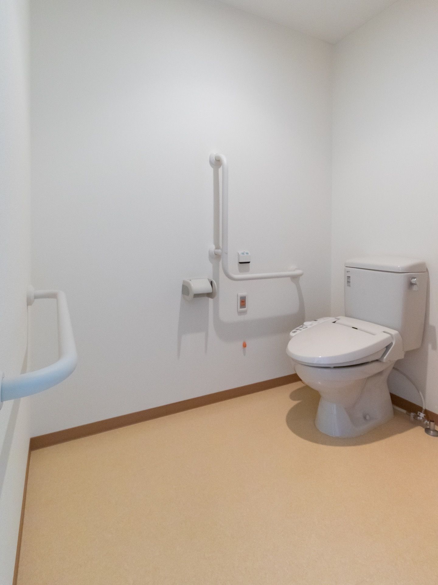 広々としたスペースのトイレである。壁にL字型の手すりがあり、つかまりながら立ち座りをすることができる。