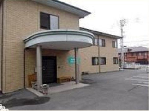 黒い玄関の横には木のベンチがあり、出かける前後に座って休憩することができる。建物の敷地内に駐車場が広く用意されている。