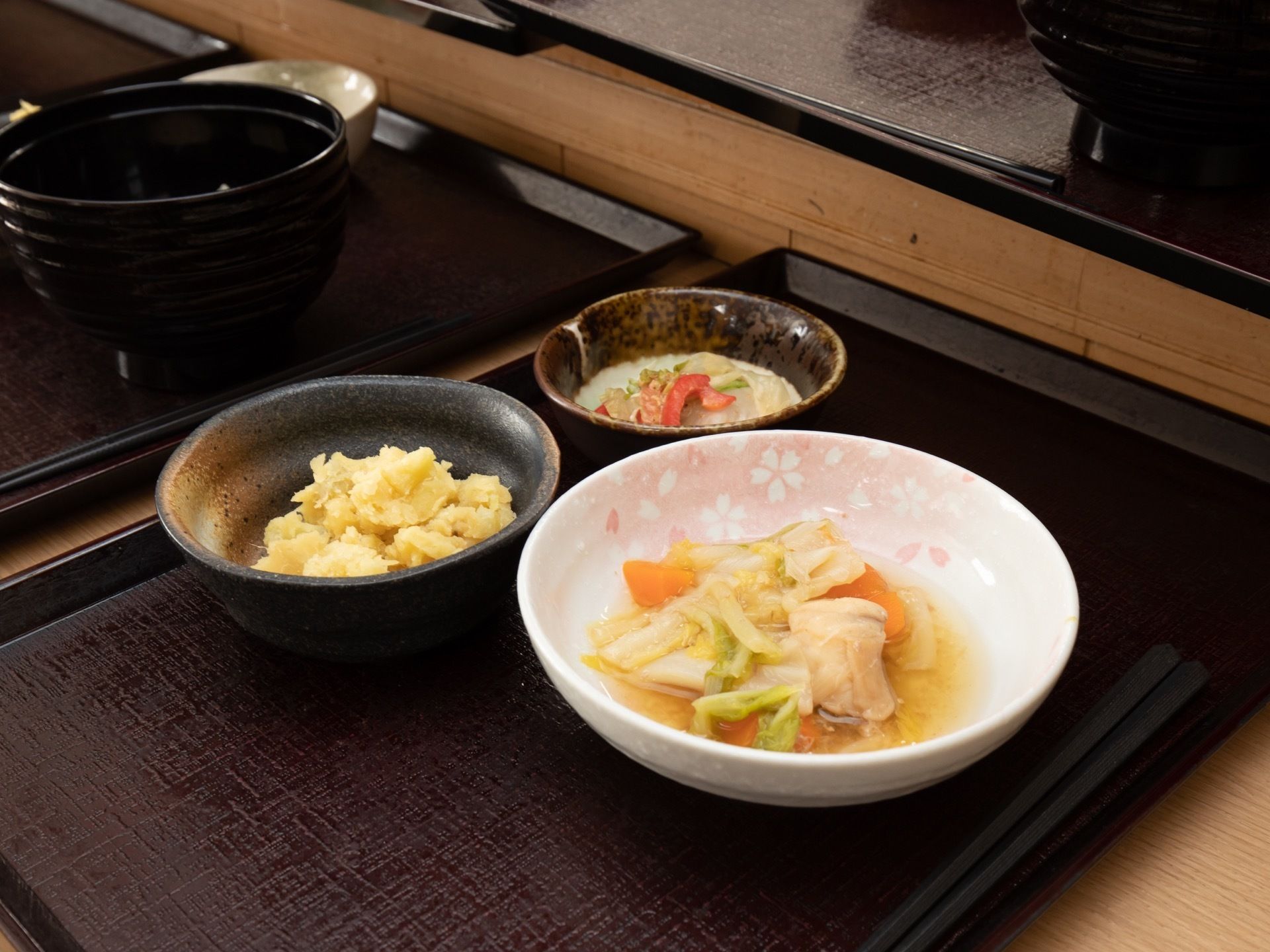 ある日の給食のメインディッシュです。ふかし芋や野菜と肉の炊き合わせ、野菜サラダである。食べ残しのない適量である。