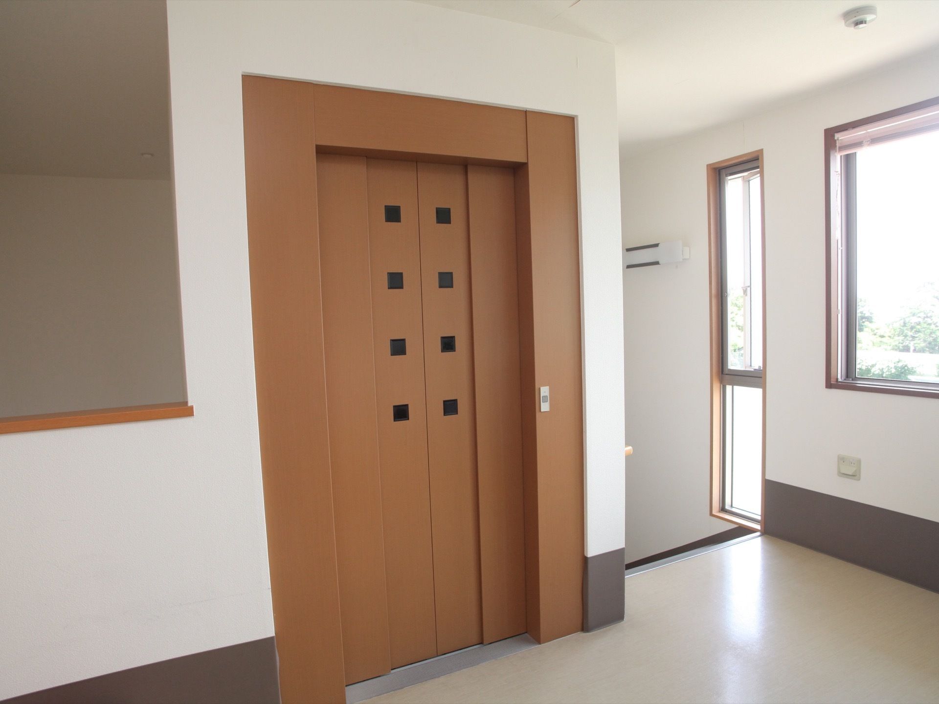 茶色いドアのエレベーターがある。フラットな出入口なので、車椅子をご利用の方でもスムーズに乗り降りができる。