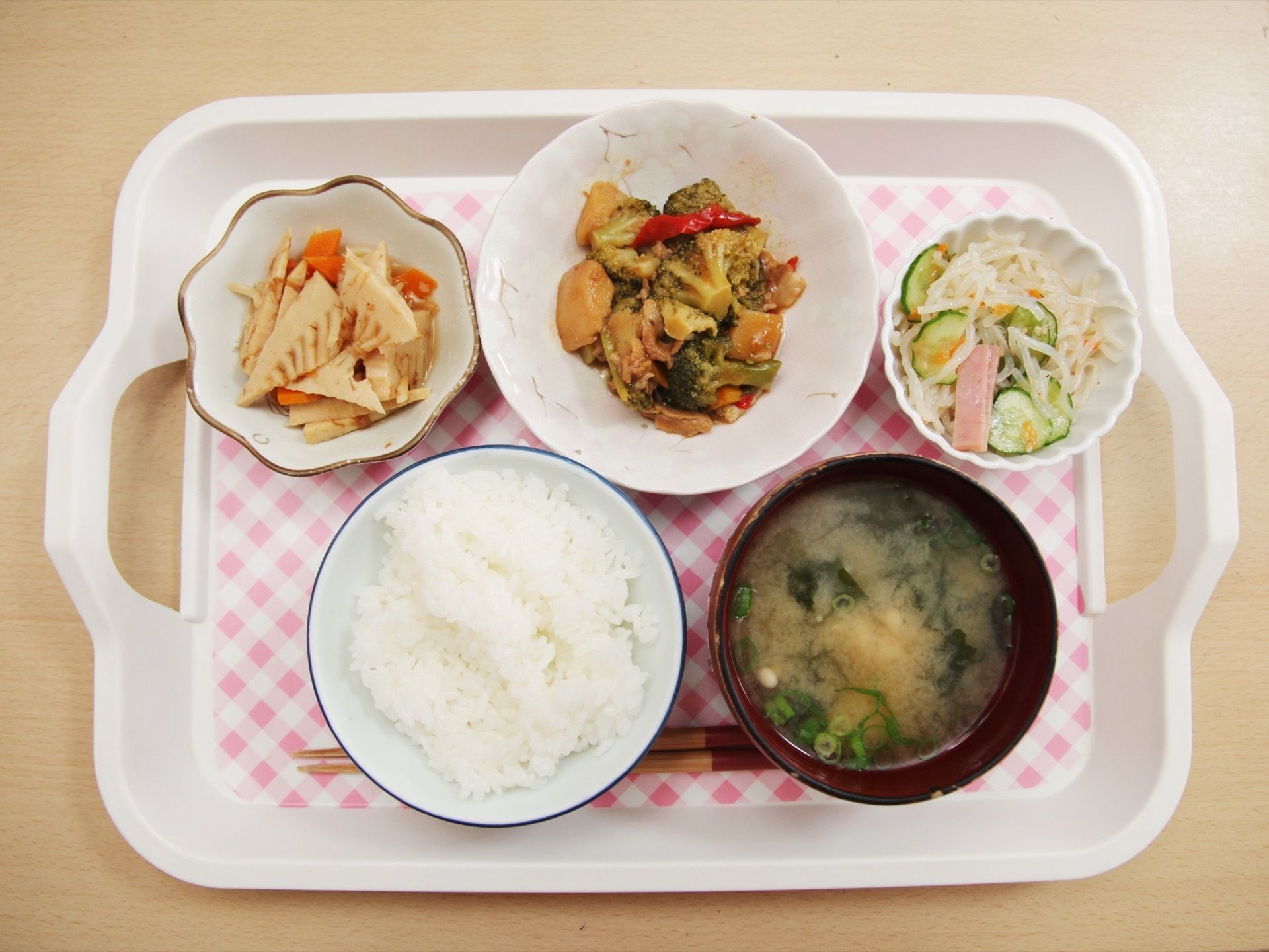 両側に取っ手の付いたプレートの上に、食事が並べられている。ご飯やみそ汁、野菜の煮物やサラダなど色彩豊かなメニューになっている。