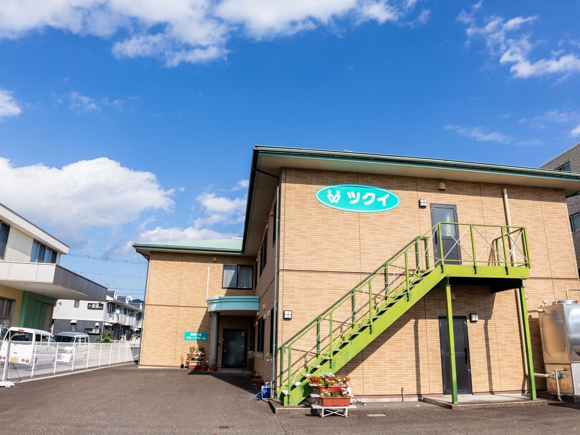 ２階建ての茶色い建物で、玄関のほかに非常用の扉、外階段がついている。周辺には似たような２階建ての建物が多くある。