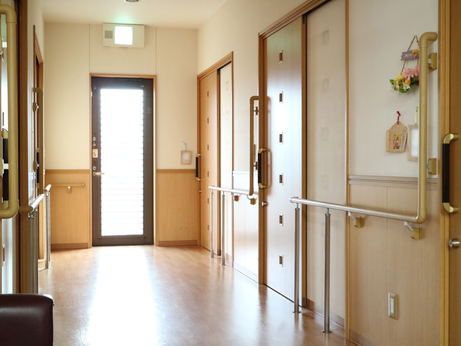 左奥に向かって伸びる廊下で、突き当たりには外へ出られる非常口のガラス扉がある。左右には引き戸が並んでいる。