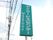 施設敷地内に立てられた看板の図である。電線が渡っているその下に、白い字で施設名が書かれた緑の看板がある。