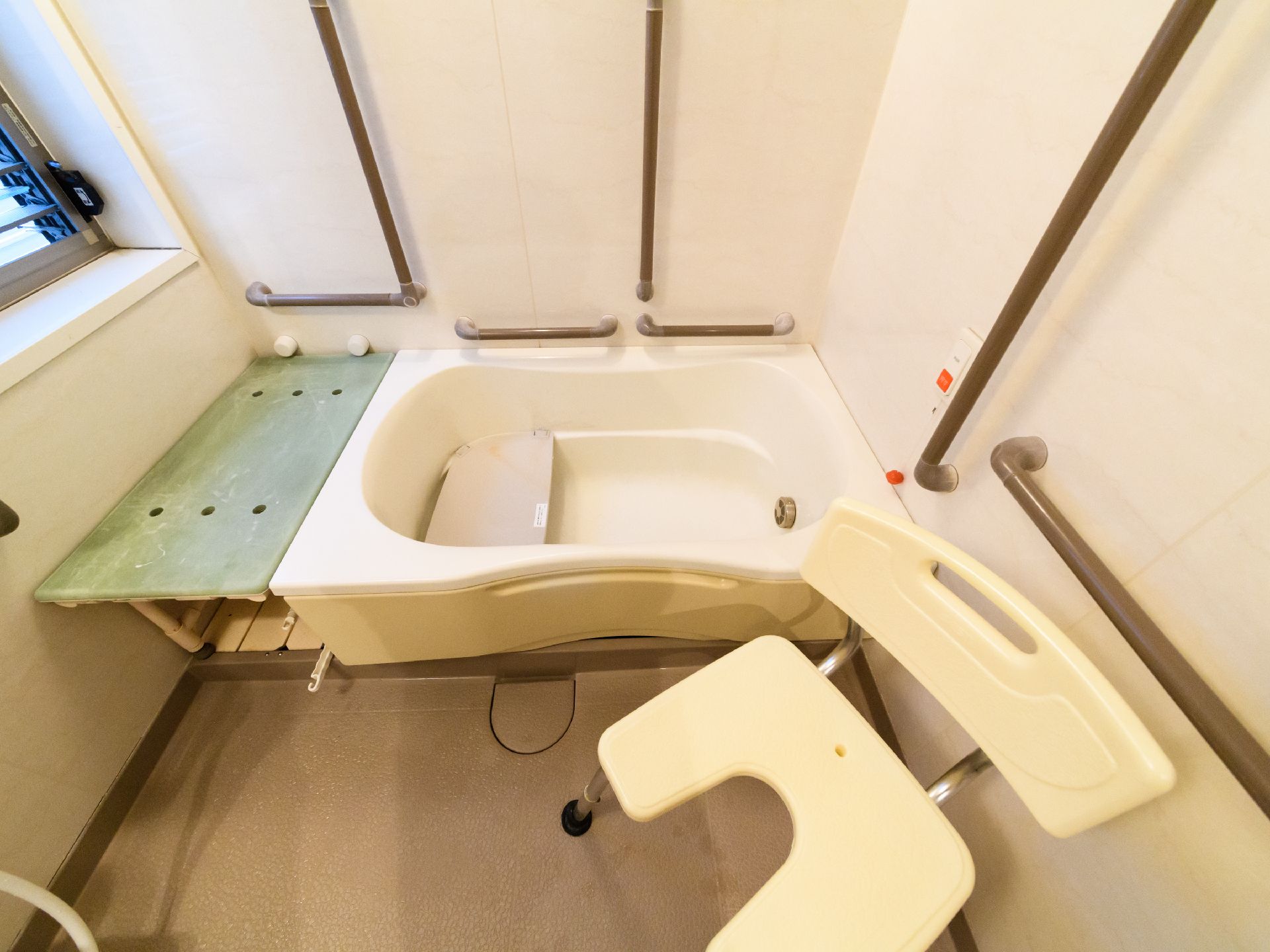 バスルームには洗い場に背もたれの付いた椅子が設けられている。座って洗えるようになっている。壁には手すりがつけられている。