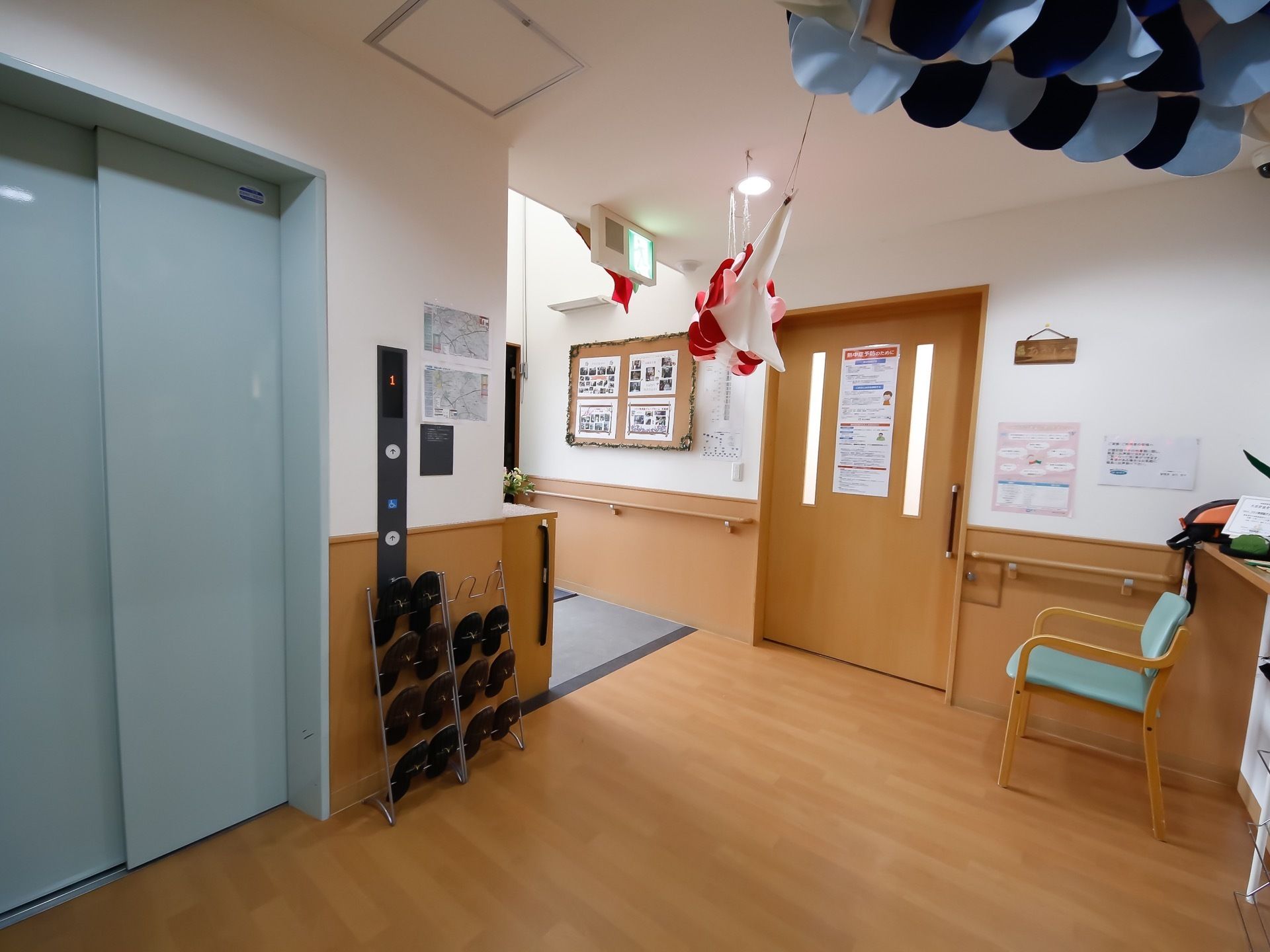 入ってすぐに掲示板があり、入って右手すぐにエレベータと来客用スリッパ、腰掛椅子が用意されている。とても明るくて清潔感がある印象を受ける。