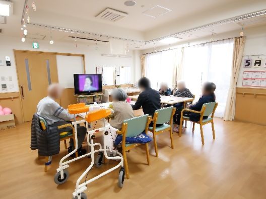 テレビを見ている入居者たち。フローリングの共有スペースにはダイニングテーブルセットが置かれている。