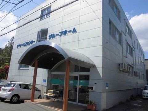 最寄り駅から徒歩圏内の場所にある白い建物の施設である。デイサービス施設を併設したグループホームである。