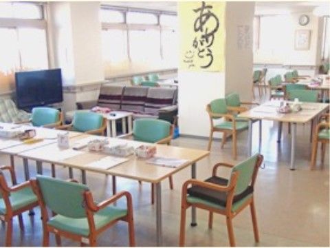 壁の多くが窓となっていて、明るい陽の光に照らされている食堂。ダイニングセットの他、テレビの側にはソファも置かれている。