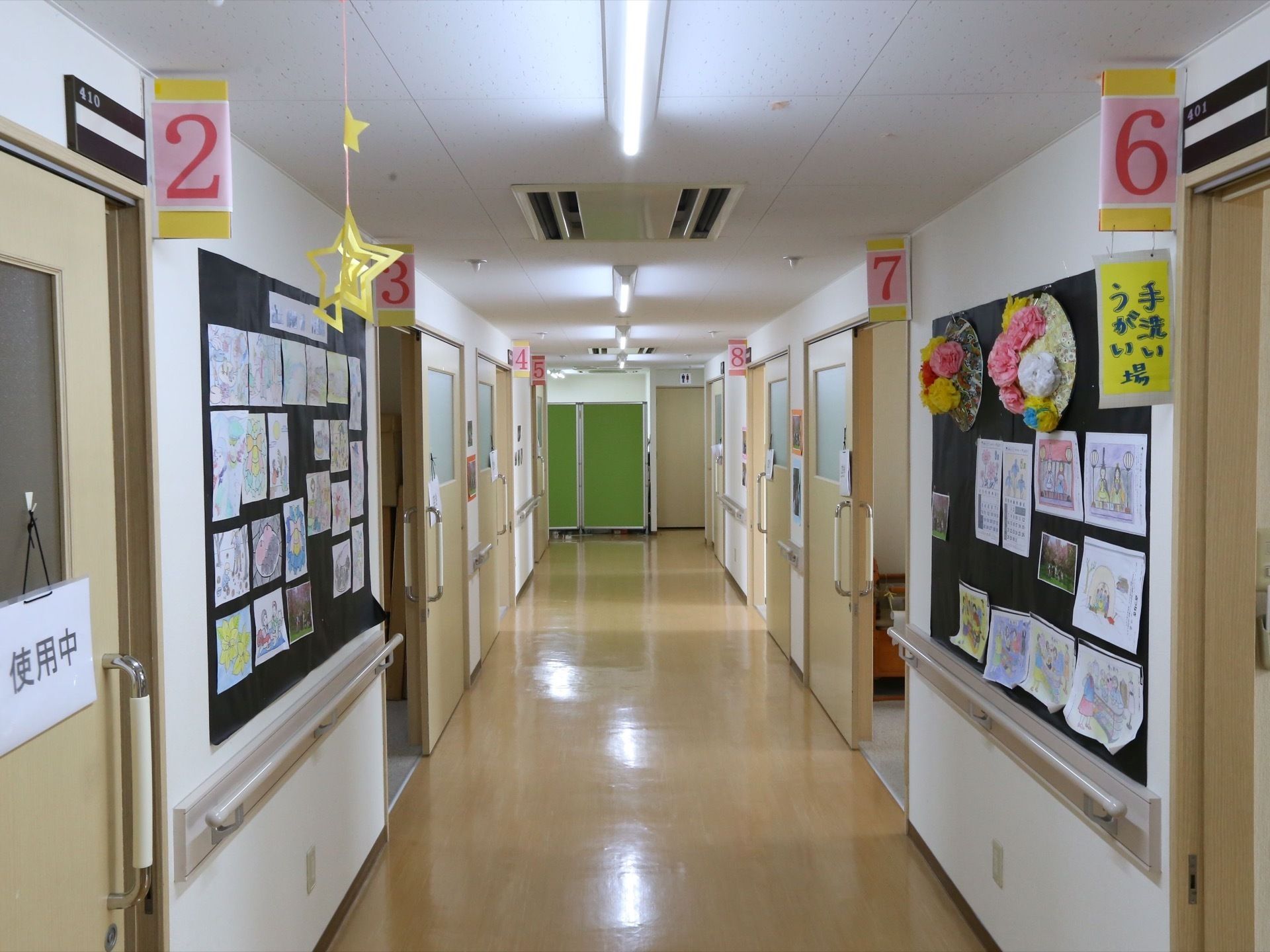 通路の左右にはそれぞれ部屋があり、番号がつけられている。壁には掲示板があり、さまざまな絵やお知らせ、飾りつけがなされている。