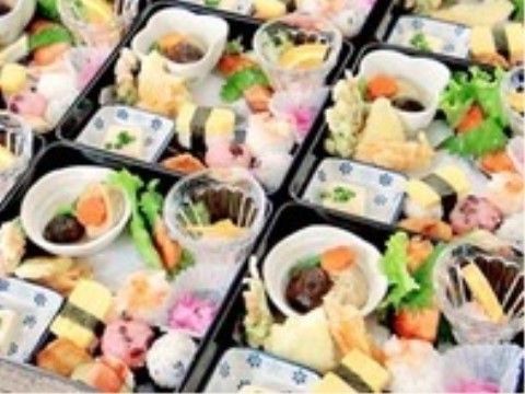 四角い器の中に綺麗に盛り付けがされている。煮物や寿司、副菜やデザートなど、色とりどりに様々な素材が味わえる。