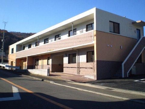 ２階建ての建物で、出入り口までは緩やかな斜面になっている外観