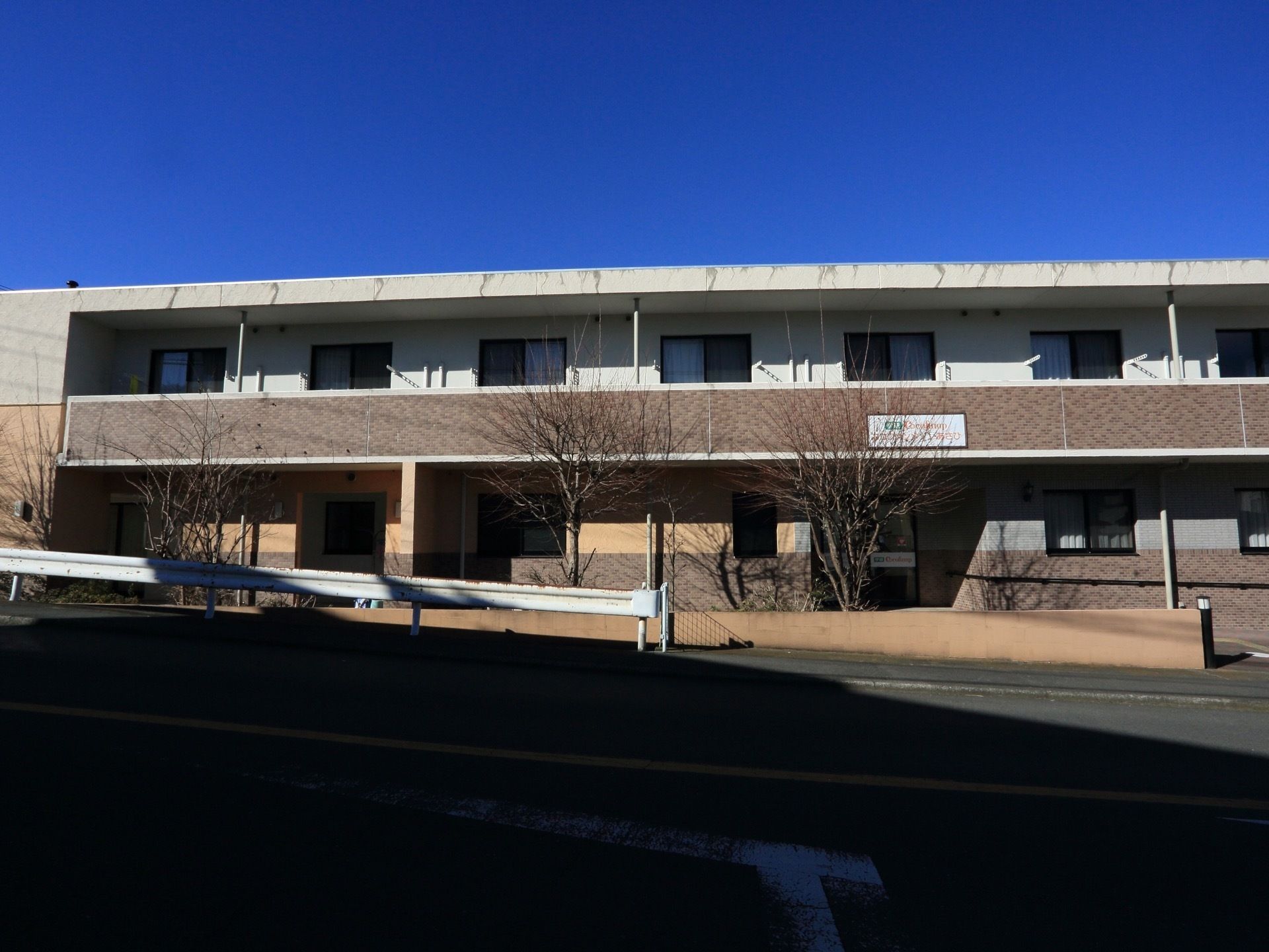 施設は２階建てになっており、落ち着いたブラウンの外壁になっている。前には木々が植えられており自然を感じることができる。