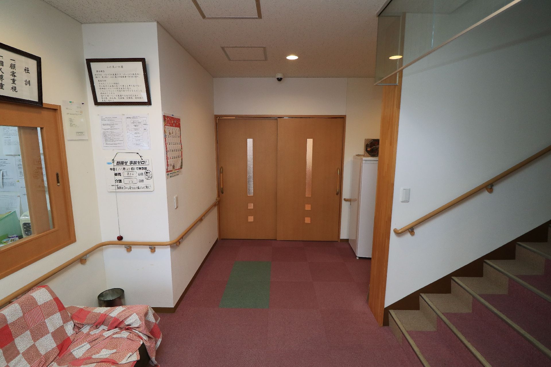 赤や白のチェック柄の布がかけられたソファが壁際に置かれている共用部