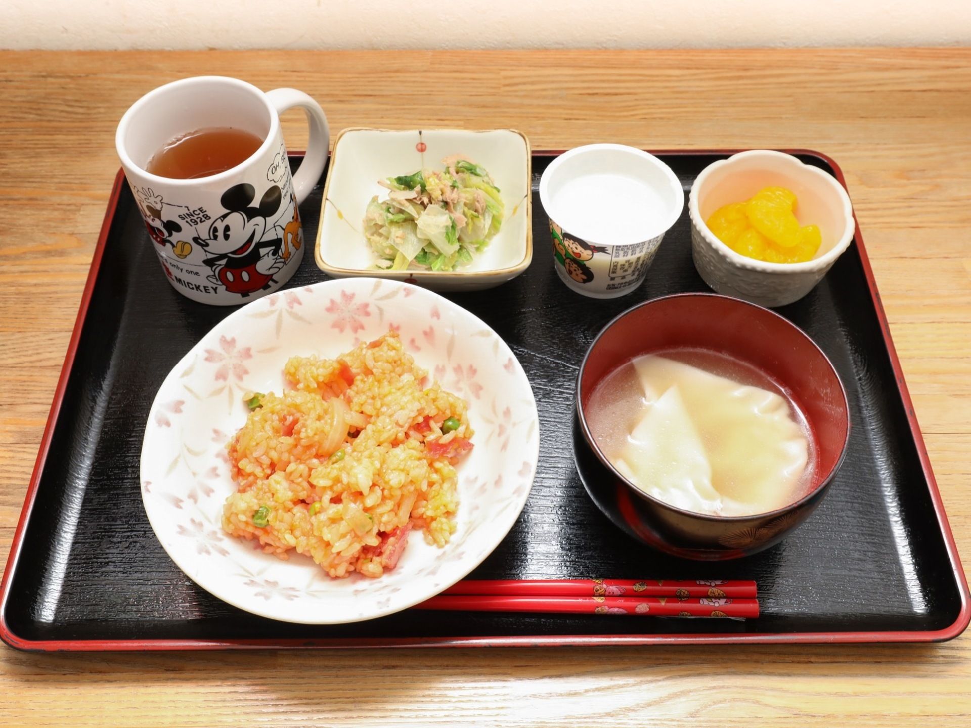 ピラフとワンタンスープ、サラダ、ヨーグルト、みかん、お茶がバランスよく盛り付けられてトレーに乗っている。