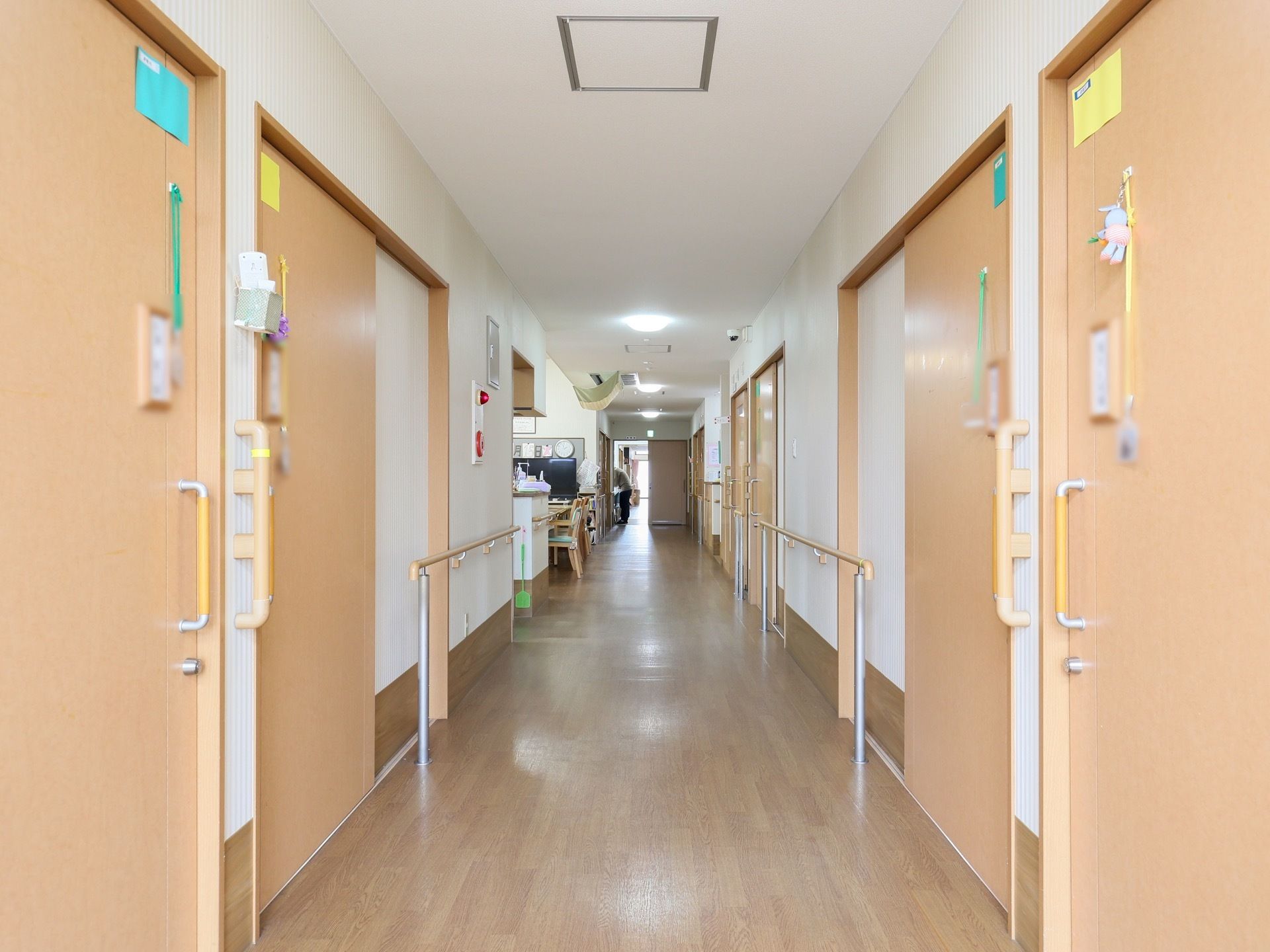 正面奥に向かって廊下がまっすぐ伸びており、両側に引き戸が並んでいる。ドアには黄色や水色の紙が貼られている。
