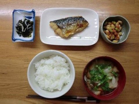 テーブルに並べられた、焼き魚や煮豆などの１人分の食事