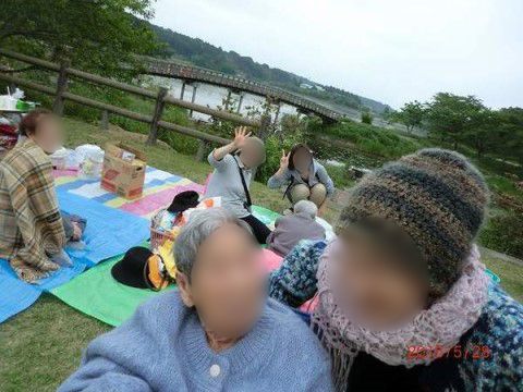大きな湖が見えている芝生の広場でシートを広げている入居者様