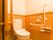 タンク手洗い器付きのトイレである。壁には、L字型の手すりと呼び出しボタン設置されている。扉は、開閉が楽なスライドドアになっている。