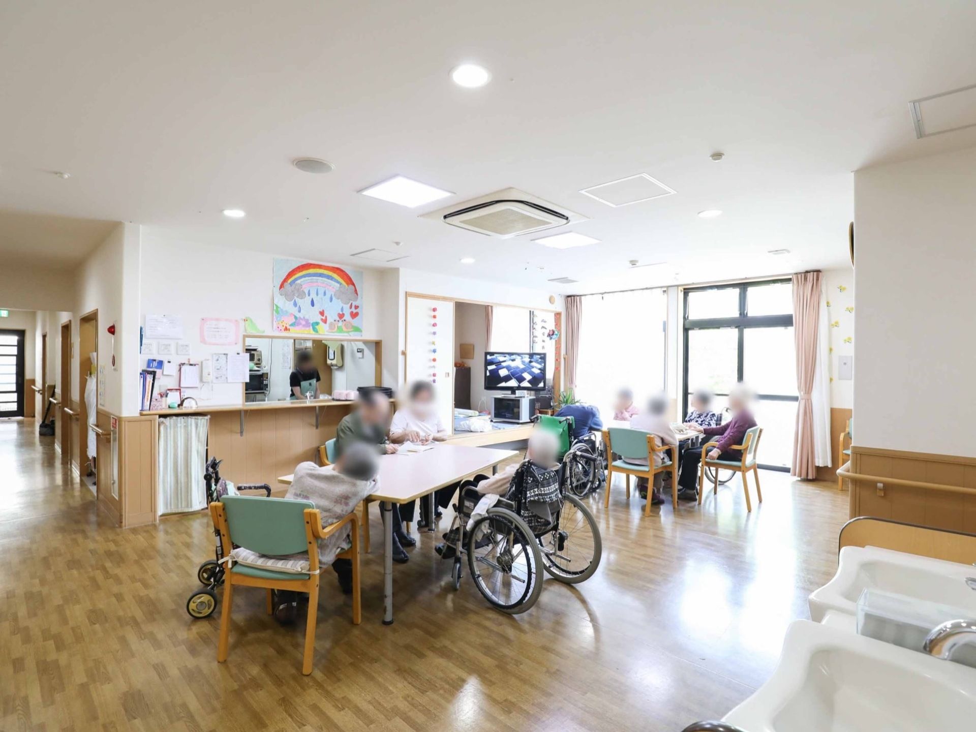 広々とした明るいスペースである。入居者様同士で、会話を楽しみながらくつろぐことができる。手前には洗面台を設置している。