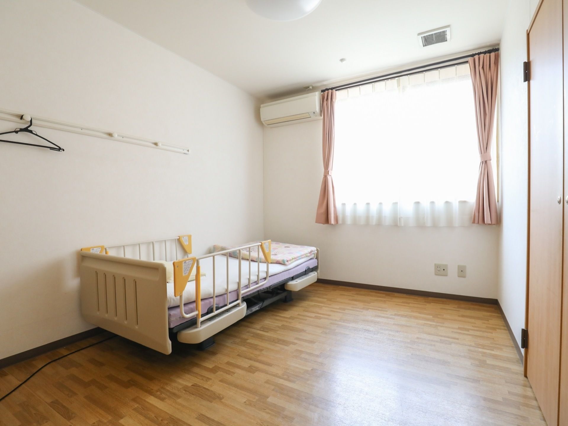 ピンクのカーテンが束ねられている、まだ入居していない部屋