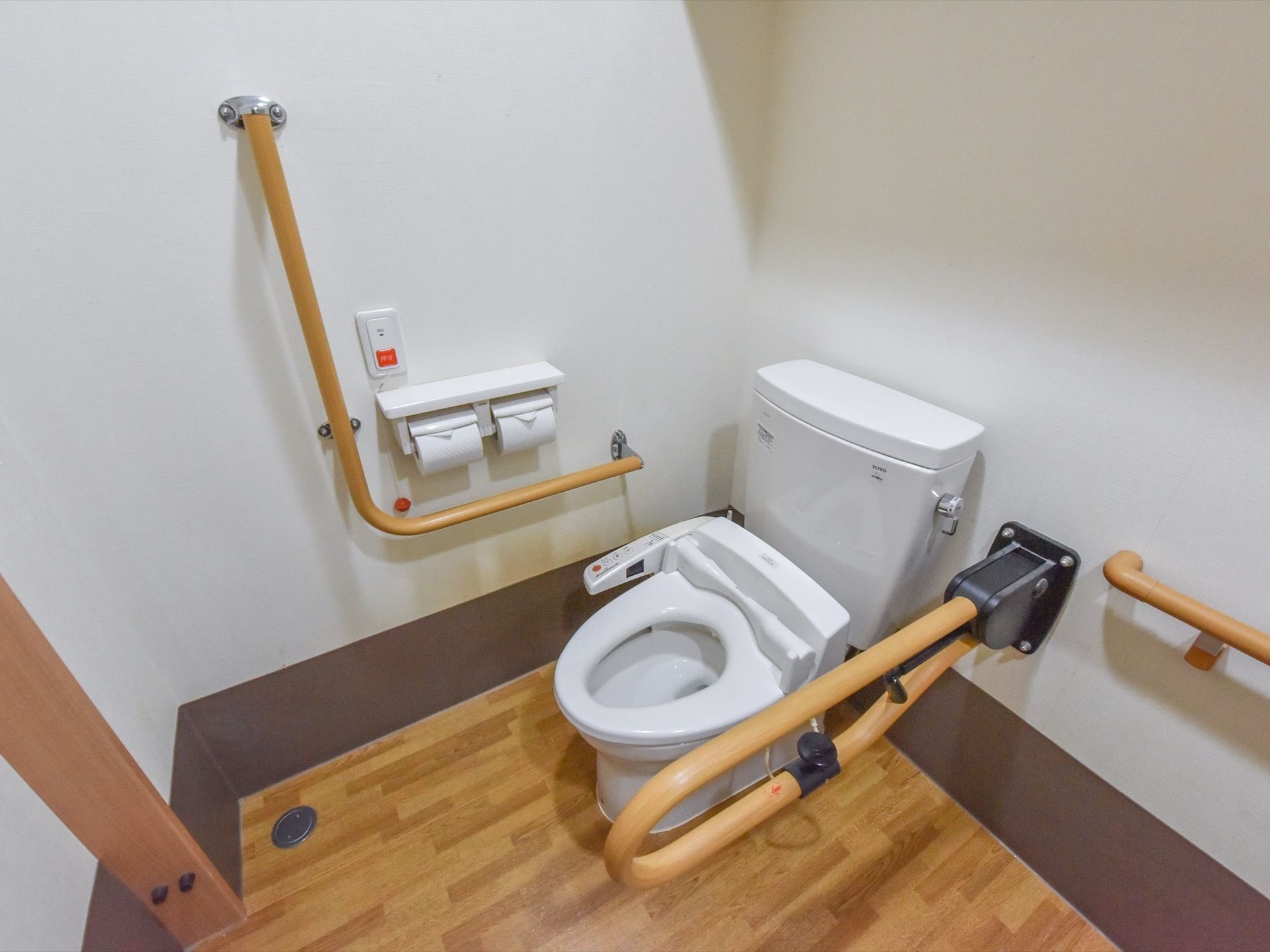 車椅子をご利用の方にも対応しているトイレである。L型や可動式の手すり、温水洗浄便座が備わっている。呼び出しボタンも設置されている。