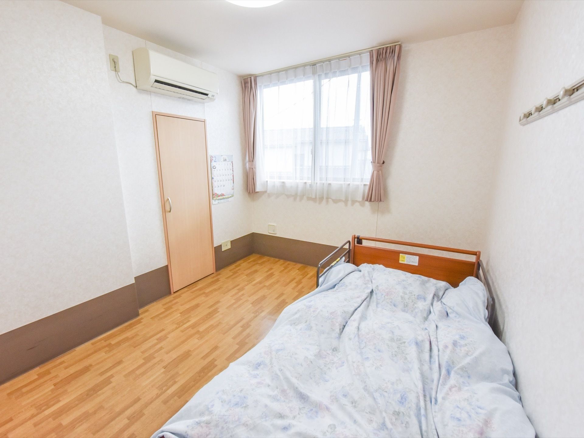 フローリングの洋室。ベッドが置かれた入居者様の居室。