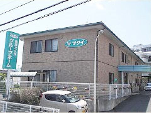 白い鉄製のフェンスで囲まれた、オレンジ色の２階建ての建物