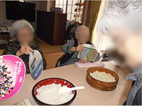 テーブルに置かれた桶に盛られた酢飯をあおいでいる入居者様