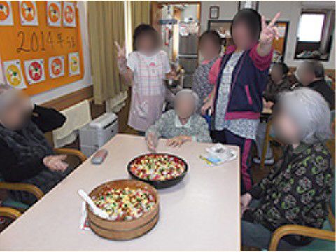 桶につくられたちらし寿司を前にポーズを取るスタッフと入居者様