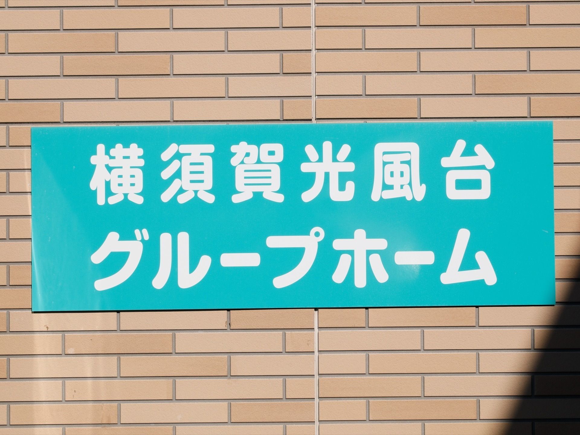 レンガ風の壁に、大きな文字で施設名の書かれた看板が設置されている。色も目立つので、探すのに迷うことはない。