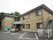 2階建ての小規模な施設の建物である。右手には外階段がある。建物の向こうには木々が見えており、自然が多い。