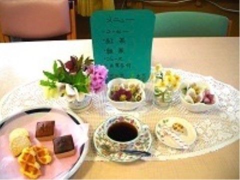 白いレースのランチョンマットの上に並ぶコーヒーやお菓子