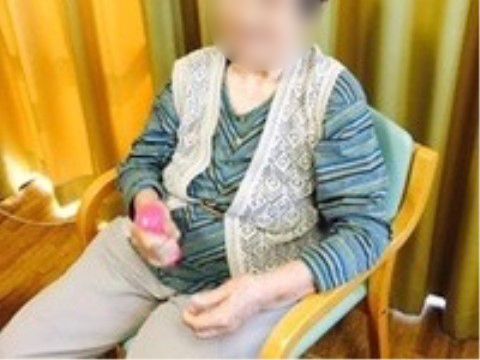 椅子に座ってピンク色のトレーニンググッズを手にしている入居者様